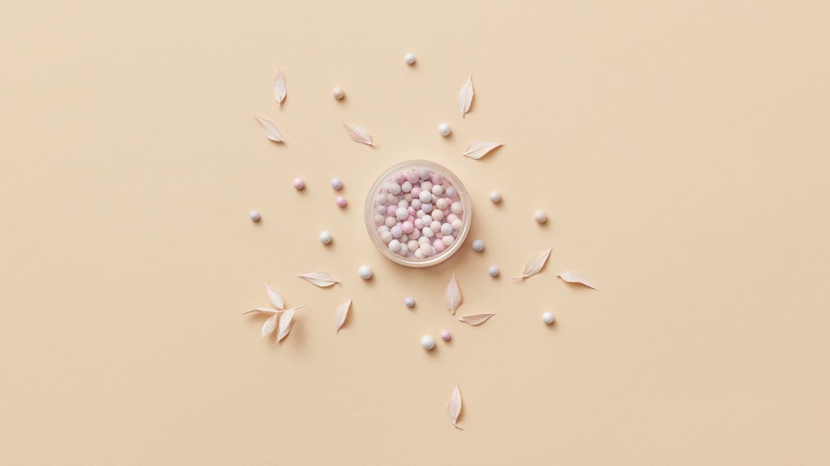 Delicate pink and white candies in a bowl with leaves on a beige background. Perfect for minimalist design.
